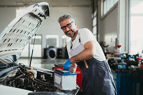 worker changing battery in car service